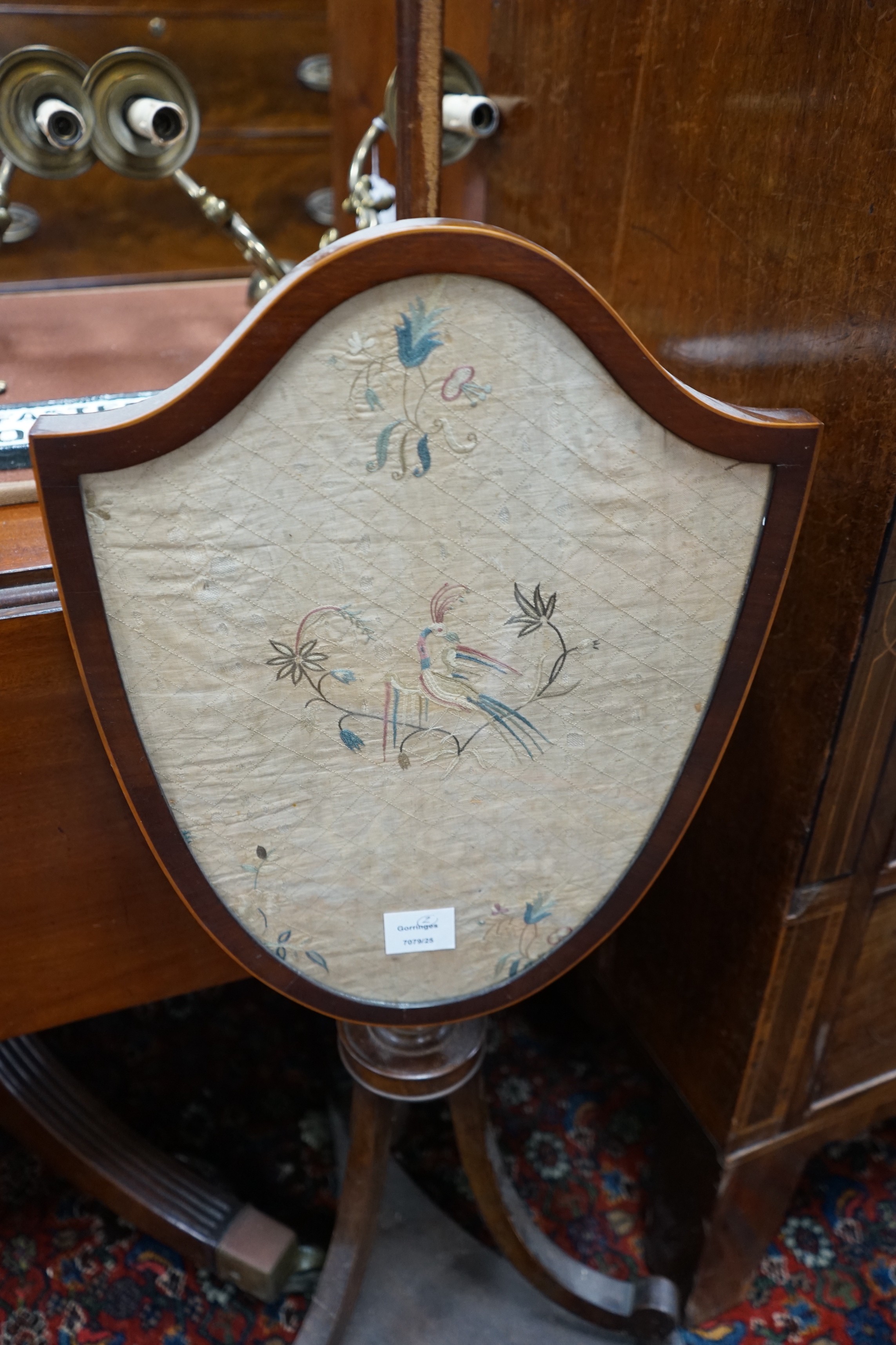 Two early 19th century shield shaped mahogany pole screens with silk embroidered banners, larger height 150cm